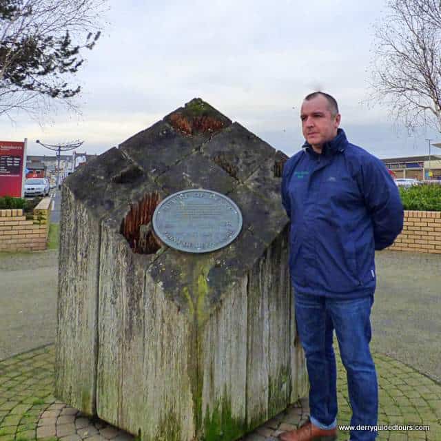 A man holding posing for the camera beside a stone marker