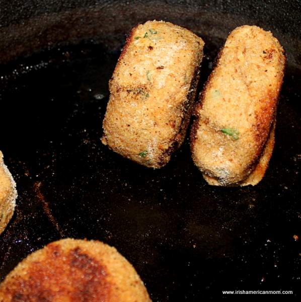 Browning the sides of thick salmon fish cake patties | Irish American Mom Frying salmon fish cakes in a black cast iron skillet