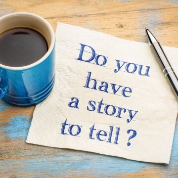 Text on a note beside a blue cup of coffee and a pen