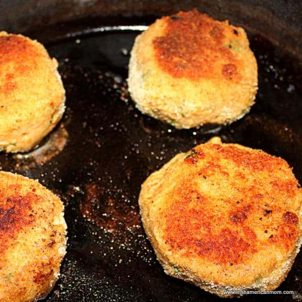 Frying salmon fish cake patties in oil in a cast iron skillet | Irish American Mom Salmon cakes sizzling in a cast iron pan