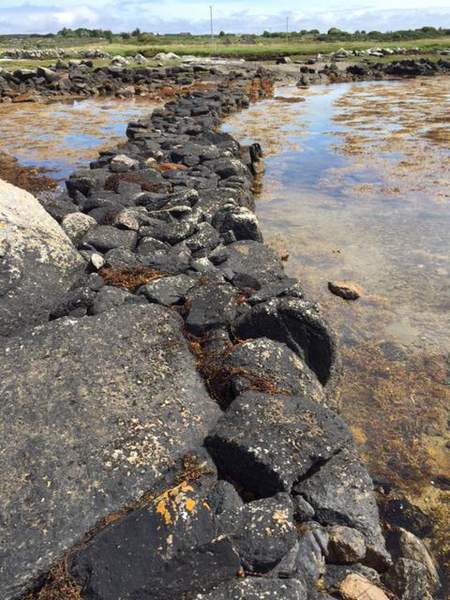 Stone path by the sea in Connemara leading to Omey Island | Irish American Mom A rocky beach next to a body of water