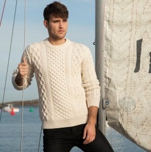 blasket-aran-sweater | Irish American Mom A man wearing a cream aran style sweater standing in front of water