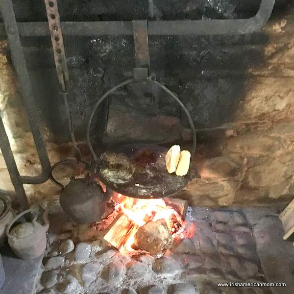 A griddle pan suspended over an open flame | Irish American Mom A griddle pan over an open fire in a stone hearth