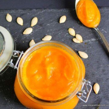 A spoon of pumpkin puree beside an open mason jar of the puree