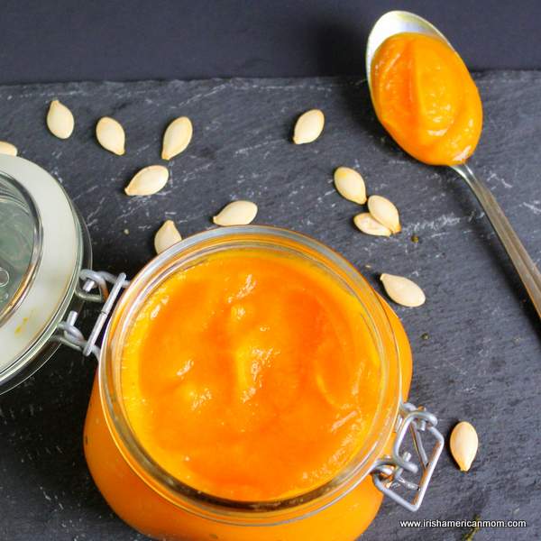 Pumpkin seeds around a spoon and open mason jar of pumpkin puree