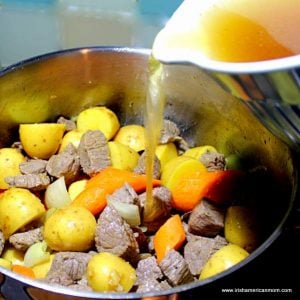 Beef broth being added to a pot of stew