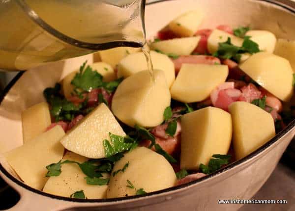 Adding stock to coddle in a pot | Irish American Mom Layered ingredients for cooking a coddle stew from Ireland