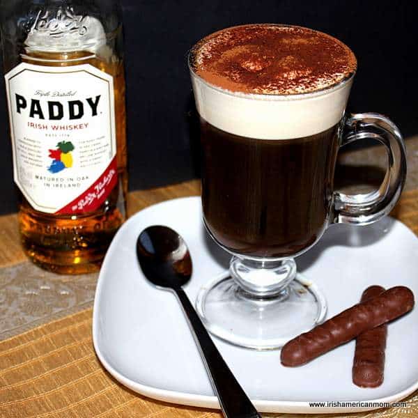 Cream topped Irish coffee with Irish whiskey | Irish American Mom Irish coffee beside a bottle of Irish whiskey