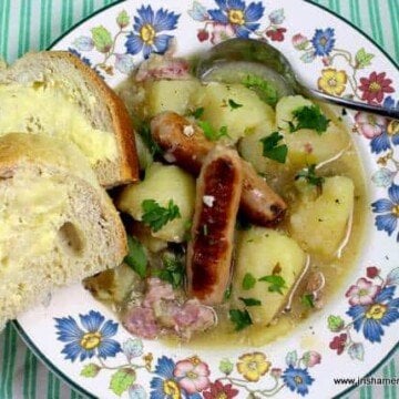 Traditional Dublin Coddle in a bowl with a spoon and slices of buttered bread