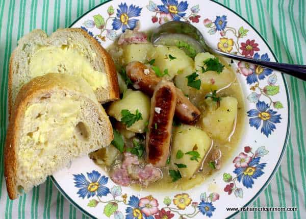 Dublin Coddle with buttered crusty bread | Irish American Mom Traditional Dublin Coddle in a bowl with a spoon and slices of buttered bread