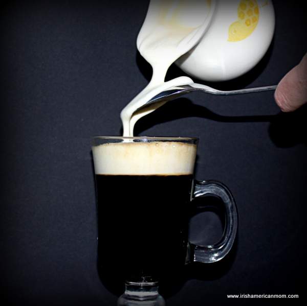 Pouring lightly whipped cream over the back of a spoon for Irish coffee | Irish American Mom Pouring lightly whipped cream over the back of a spoon to float on the top of a glass of black coffee