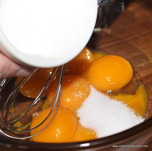 Adding sugar to egg yolks for Baileys Creme Brulee | Irish American Mom Adding sugar to eggs in a bowl