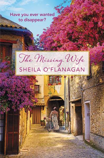 Book Cover for The Missing Wife by Sheila O'Flanagan | Irish American Mom A book cover featuring a street scape with cherry blossoms