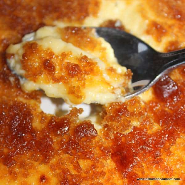 Caramalized sugar on top of creme brulee | Irish American Mom A close up of a spoon of creme brulee with a cracked sugar crust