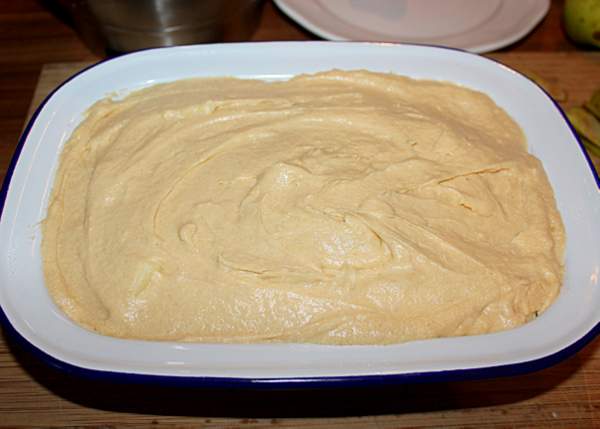 Cover apples with sponge batter before baking for Eve's puding | Irish American Mom Sponge topping on a pudding in an enamelware casserole dish.