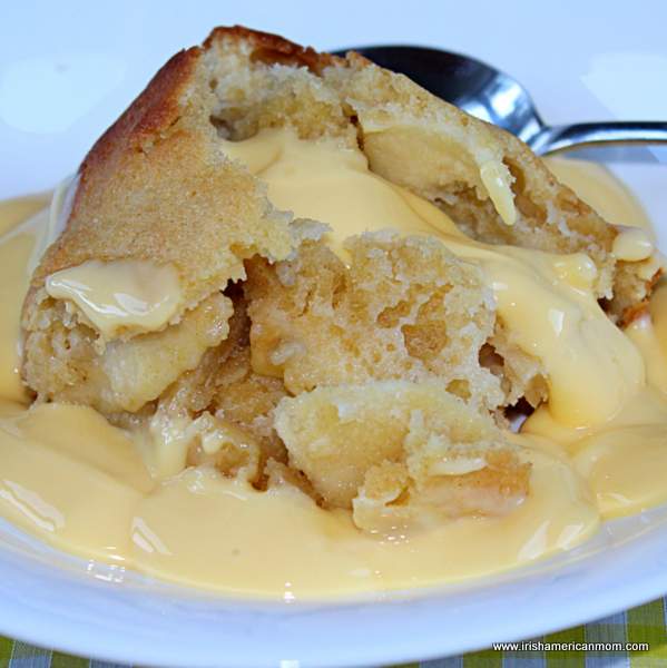 Eve's pudding served with custard | Irish American Mom Apple and sponge pudding topped with yellow custard sauce with a spoon.