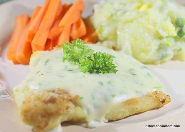 Cod and parsley sauce with champ and steamed carrots and mashed potatoes | Irish American Mom Flour dredged cooked cod piece covered in parsley sauce and garnished with parsley