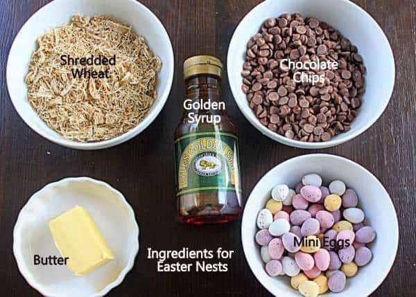Ingredients for chocolate Easter nests | Irish American Mom Ingredients needed to make chocolate Easter nests including bowls of shredded wheat, chocolate chips, butter, syrup and mini Easter eggs