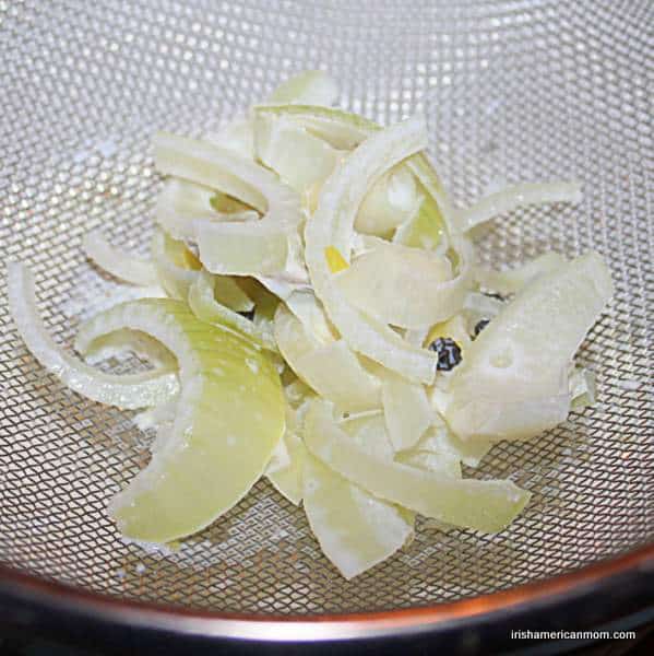 Straining infused milk for parsley sauce | Irish American Mom Draining milk through a sieve to separate the aromatics in poaching liquid.