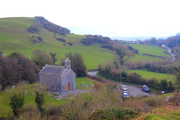 Holy Trinity Church and the Rock of Dunamase | Irish American Mom A church beside a green hill with cars parked beside it