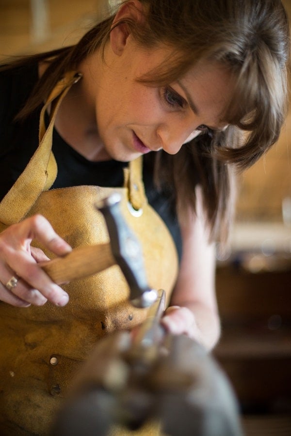 A woman using a hammer to shape a ring