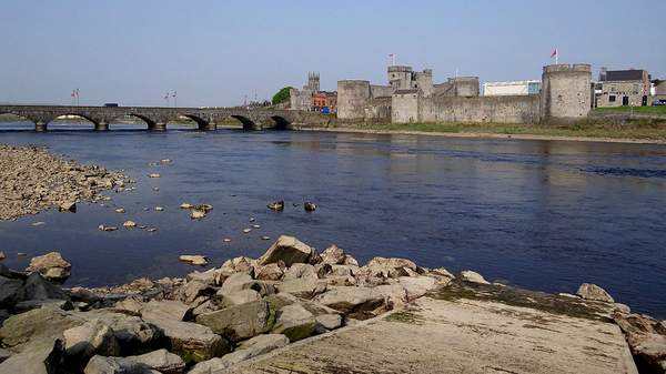 A bridge over a body of water beside a stone castle