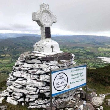 Stone cross on a mound of rocks on top of a mountain