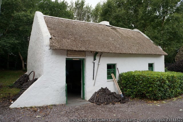 Peat or turf outside a small cottage with a thatched roof