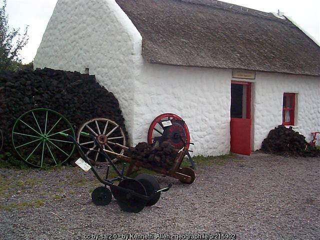 Peat outside a cottage with white walls and a red door