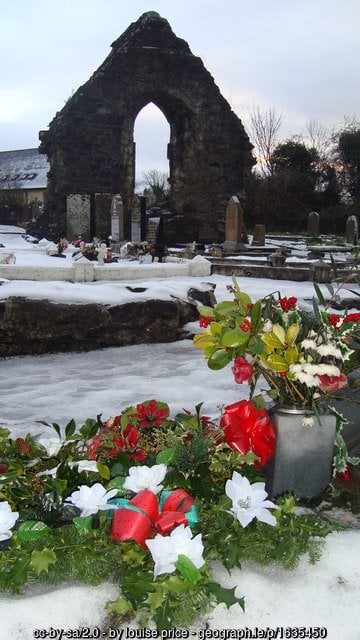 A grave with holly wreaths at Christmas time in Ireland | Irish American Mom Wreaths and plants on a grave in a cemetery