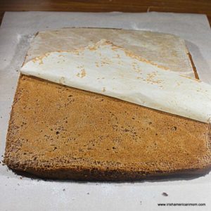 peeling parchment paper off a chocolate cake