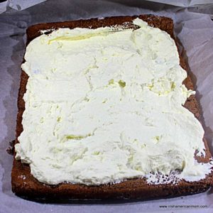 A piece of chocolate cake with fresh cream spread on top