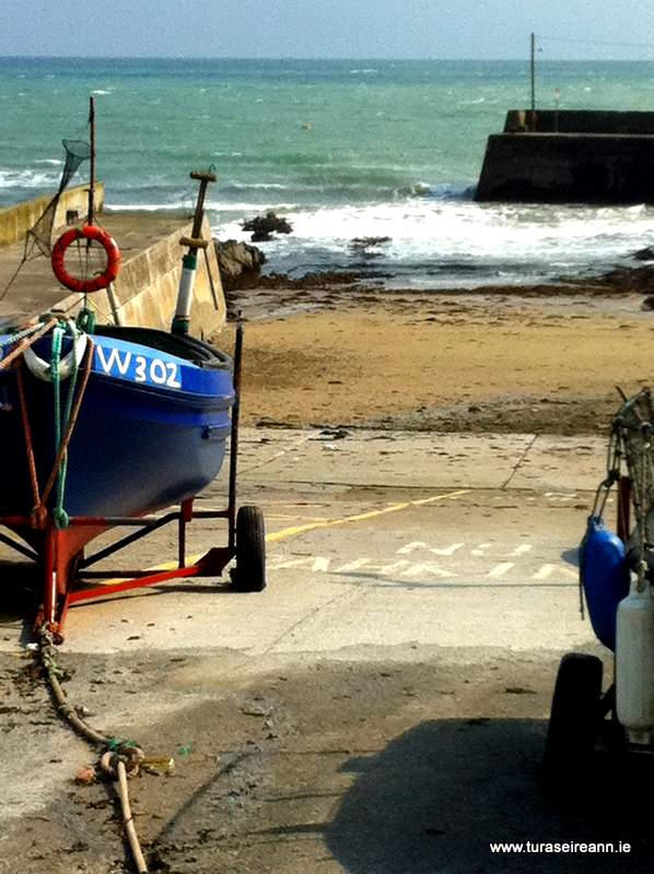 An Irish pier with a blue boat on a trailer