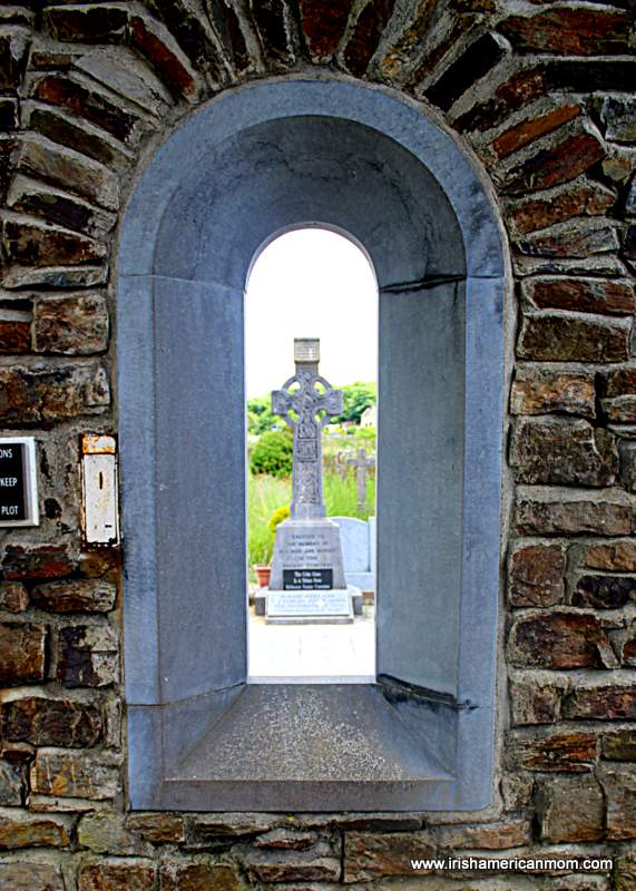 Celtic cross viewed through an arched opening on a stone wall