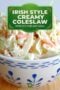 Bowl of creamy cruncy cabbage coleslaw with a green text banner overlay featuring white text and Celtic designs.