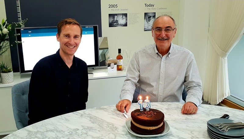 Two men sitting at a table with a cake