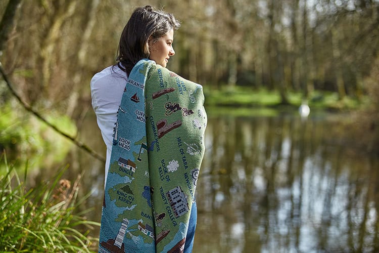 A woman drapes a cotton throw over her shoulder, featuring a map of Ireland