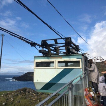 A blue cable care being boarded by people