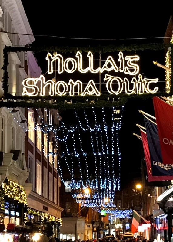 Nollaig Shona Duit sign off Grafton Street in Dublin Ireland | Irish American Mom A Happy Christmas sign in Irish illuminated over the streets of Dublin