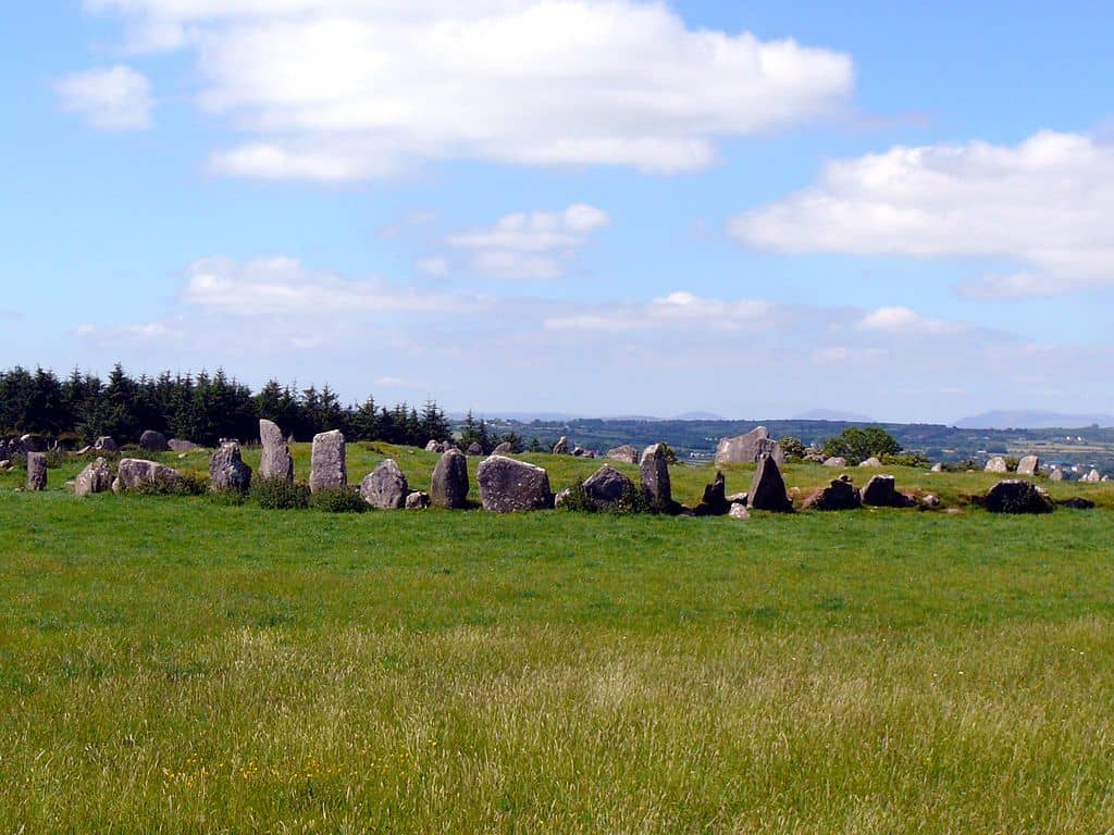 A few of the full circle at Beltany an ancient Celtic site in County Donegal | Irish American Mom Standing stones in a wide circle in a green Irish field under blue skies with fluffy clouds