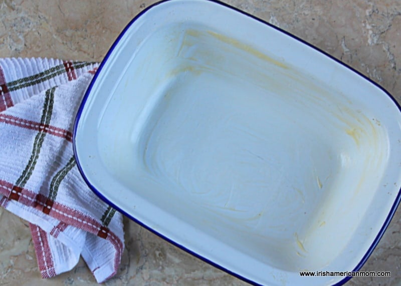 Greasing an enamel ware pie dish to make rhubarb crumble | Irish American Mom A white enamel ware casserole with a navy blue trim greased with butter