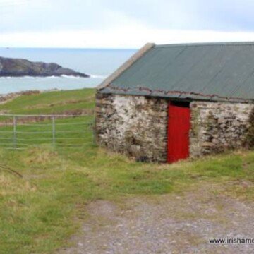 An iron gate beside an old shed with a red door on the coast