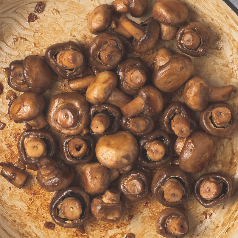 Caramalized mushrooms in a skillet with garlic | Irish American Mom Mushrooms caramelizing to a golden brown color in a pan