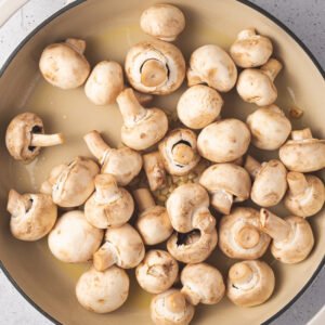 Cleaned white mushrooms with stems in a pan