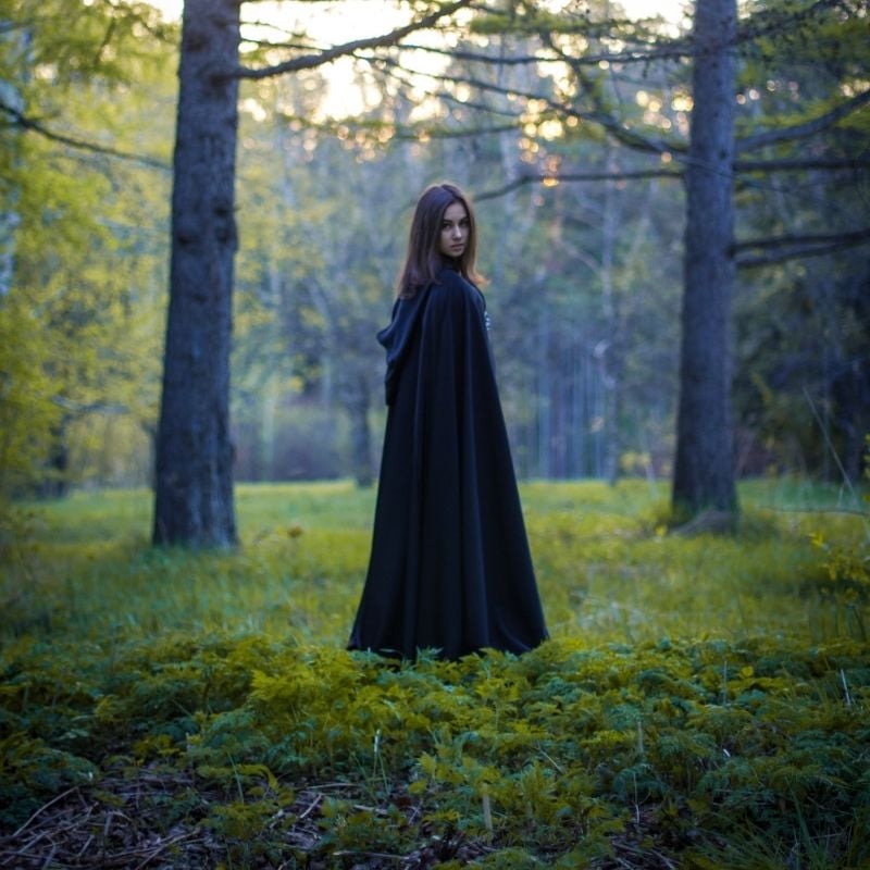 Black cloak as a Halloween costume | Irish American Mom A girl in a black cloak standing in a forest