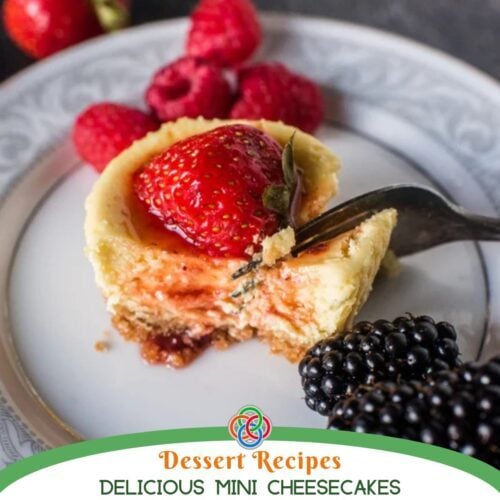 Close-up of a mini cheesecake topped with a fresh strawberry, served with raspberries and blackberries on a patterned plate with text banner.