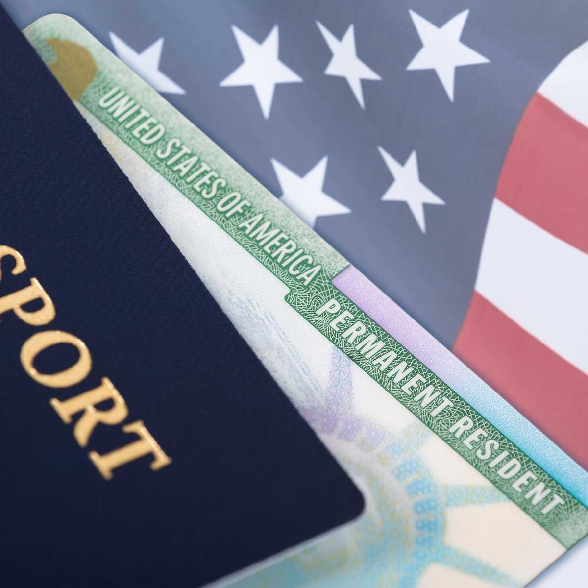 United States resident alien or green card with a passport | Irish American Mom A green card or resident alien card with a US passport against a backdrop of the American flag