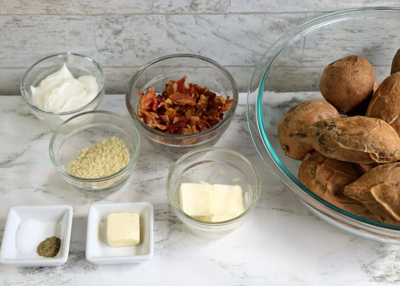 Ingredients for Twice Baked Sweet Potato Casserole with Bacon | Irish American Mom Baked sweet potatoes in a bowl beside bowls with sour cream pecans, panko, butter and salt and pepper