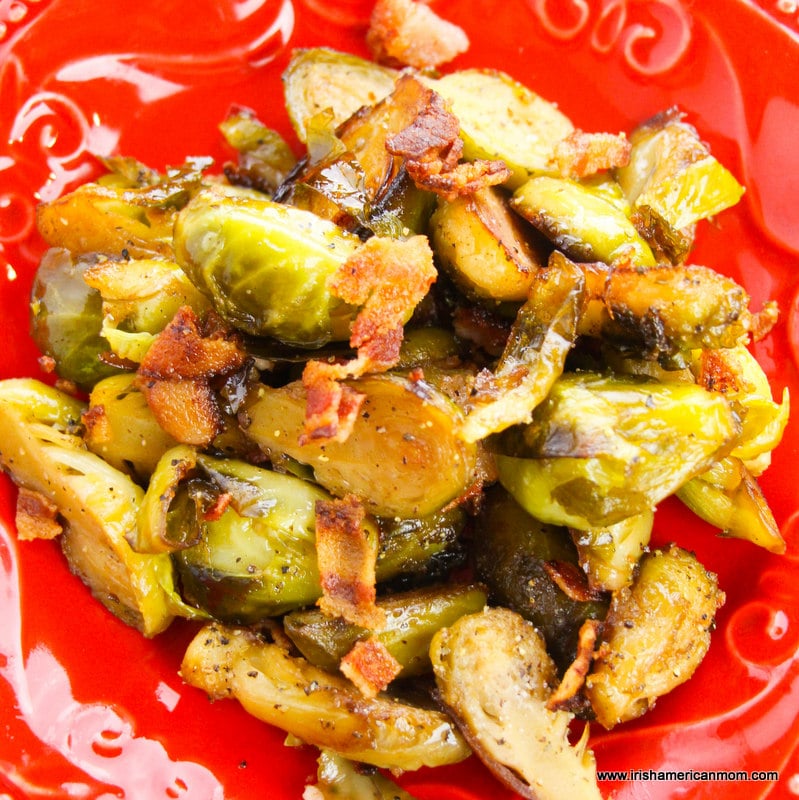 Maple bacon Brussels sprouts in a red serving dish | Irish American Mom Brussels sprouts with bacon bits served on a red platter
