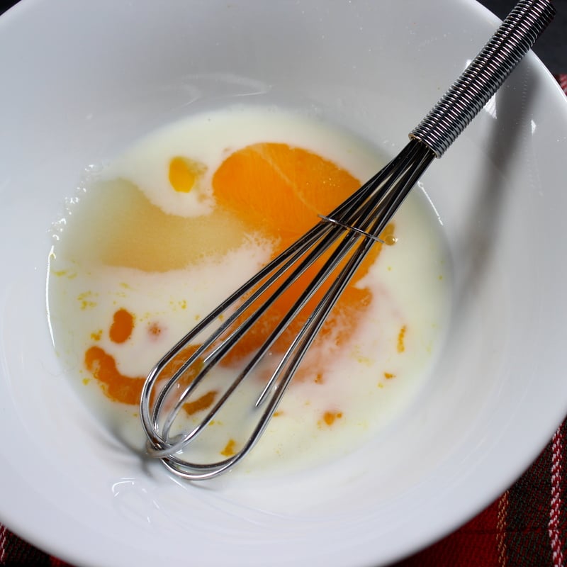 Stirring egg yolk, milk and sugar in a bowl for a glaze for a barmbrack